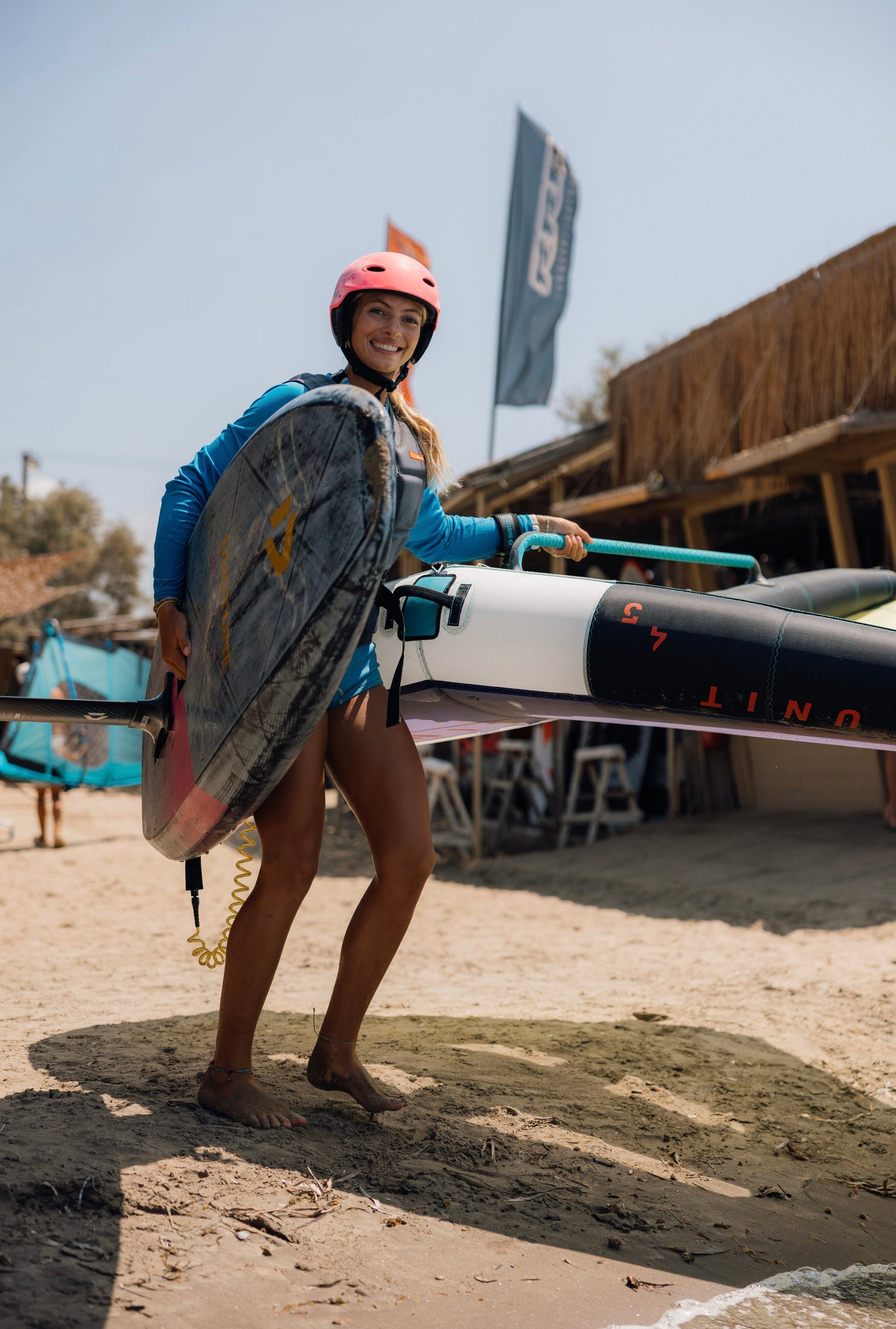 Wingfoil, vrouw met surfspullen, roze helm, surfclub